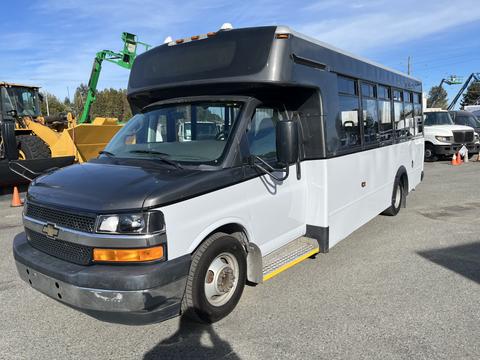 A 2017 Chevrolet Express with a black front and white body designed for passenger transport featuring large side windows and a low step entrance