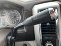 Close up of the gear shift lever in a 2010 Dodge Ram showcasing a black handle with a button and surrounding dashboard features