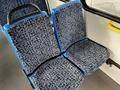 Blue and black patterned bus seats with a handrail visible in the background