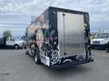 A black 2011 Ford Utilimaster Food Truck featuring colorful food-themed graphics on the side and a silver service window in the rear