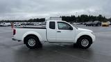 A white 2016 Nissan Frontier pickup truck with a bed and single cab parked on a lot