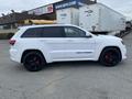 A white 2018 Jeep Grand Cherokee with black alloy wheels and red brake calipers viewed from the side