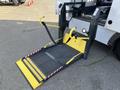 A yellow wheelchair ramp deployed from the back of a 2017 Chevrolet Express with safety straps attached