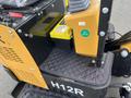 A 2024 AGT Mini Excavator showcasing a yellow and black exterior with a prominently displayed H12R label and a control panel featuring a yellow box and a green quality check sticker