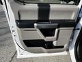 The interior door panel of a 2017 Ford F-150 featuring a handle, armrest, and storage compartments in a light color scheme
