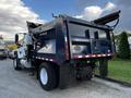 A 2011 International 7300 truck with a raised dump bed and a dark blue body parked on a paved surface