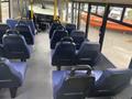 Interior view of a 2018 Chevrolet Express showing blue seats arranged in rows facing forward with a driver's area visible at the front