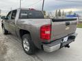 A 2013 Chevrolet Silverado Hybrid in a metallic gray color parked on a road with visible wheels and a rear view showcasing the truck bed and tailgate