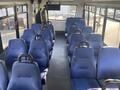 Interior view of a 2018 Chevrolet Express featuring blue upholstered seats arranged in a single isle layout with a TV monitor at the front