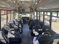 Interior view of a 2018 Chevrolet Express with a row of seats on either side and a driver's area visible at the front