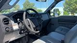 Interior view of a 2011 Ford F-450 SD showing the dashboard steering wheel and seats with a focus on the driver's side controls and layout.