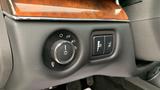 Close-up of a Lincoln MKT dashboard featuring control knobs for lights and a trunk release button with a wood-paneled accent