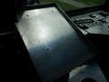 A metallic platform with a smooth surface and visible screws on top placed inside a vehicle