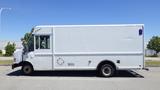 A white 2006 Ford Econoline van with a boxy design and large side doors parked with no visible markings except for a small logo on the side