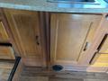 A section of wood cabinetry with two doors and a granite countertop featuring a sink in a vehicle interior