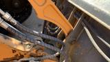 A close-up of hydraulic lines and joints on a 2015 Case 580 heavy machinery arm