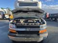 A 2012 Chevrolet Express with the hood raised revealing the engine compartment and various mechanical components inside