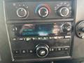 Close-up of the dashboard controls of a 2018 Chevrolet Express featuring buttons for radio settings and climate control with a digital display showing station and time