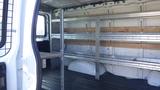 Interior view of a 2015 GMC Savana cargo van featuring metal shelving units and wooden planks along the sides