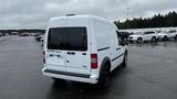 A white 2012 Ford Transit van with a blank rear license plate and tinted windows parked on a lot