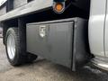 A gray storage box mounted on the side of a 2015 Ford F-550 truck with a lock on the front and a single tire visible underneath