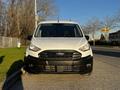 A white 2022 Ford Transit Connect van is parked with its front view facing the camera showcasing a black grille and headlights