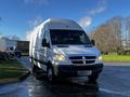 A 2008 Dodge Sprinter Van with a white exterior and a high roof parked on a wet surface