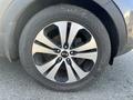 A close-up of a black and silver alloy wheel from a 2012 Kia Sportage with a tire that appears slightly worn and dirt on the wheel surface