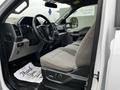 The interior of a 2017 Ford F-150 featuring a driver's seat with grey fabric upholstery and a steering wheel with controls