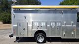 A silver 2005 Morgan Olson Workhorse with several compartments on its side and a yellow awning extended from the top