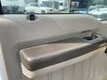 A close-up of the armrest on the door panel of a 2010 Ford F-550 showing a textured surface in a light color