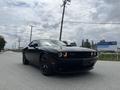 A black 2017 Dodge Challenger parked on a road with distinctive headlights and sleek design