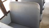 Gray vinyl bus seat with a high backrest typical of school buses