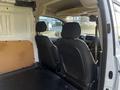 Interior view of a 2022 Ford Transit Connect showing front passenger and driver seats with a minimalist design and a spacious cargo area behind