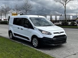 A white 2016 Ford Transit Connect van is parked with sliding side doors and five wheels visible on a street with trees in the background