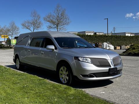 A silver 2013 Lincoln MKT conversion vehicle with a sleek design features a long body and customized rear section for passenger transport