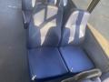 Two blue upholstered seats with a mesh pattern on a bus interior