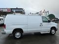 A white 2014 Ford Econoline van with side doors and roof rack showcasing a clean design and metallic wheels