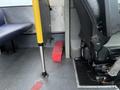 A red toolbox placed on the floor between a bus driver's seat and a partition wall with a metallic surface