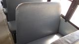 A gray bus seat in a 2014 International 3000 model with a rounded back and textured upholstery