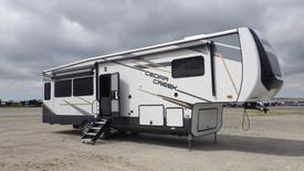 A 2021 Forest River Cedar Creek fifth-wheel RV with a sleek exterior design featuring large windows and a slide-out area for added space