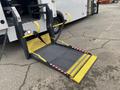 A wheelchair lift with a yellow and black platform deployed from a 2017 Chevrolet Express van