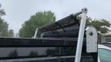 A close-up of the rear of a black 2021 International CV515 truck showcasing its rolled-up tarp secured by a metal frame