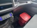 A red plastic container sitting on the floor of a vehicle's interior next to a control panel with buttons and a display