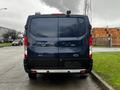 A blue 2020 Ford Transit van parked with its rear facing the viewer showcasing its model name and tail lights