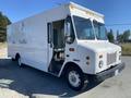 A white 2006 Workhorse W42 delivery truck with large windows and a simple front design parked on the side of a road