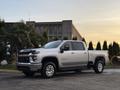 A silver 2023 Chevrolet Silverado 3500HD with a double cab and chrome wheels parked at an angle