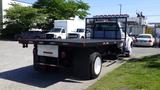 A 2006 Ford F-650 flatbed truck with a black bed and white cab parked in a lot