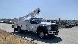 A 2011 Ford F-450 SD bucket truck equipped with a raised aerial platform and utility service body