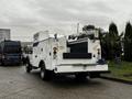 A 2015 Ford F-550 service truck with a white exterior featuring various compartments and equipment on the rear for utility work